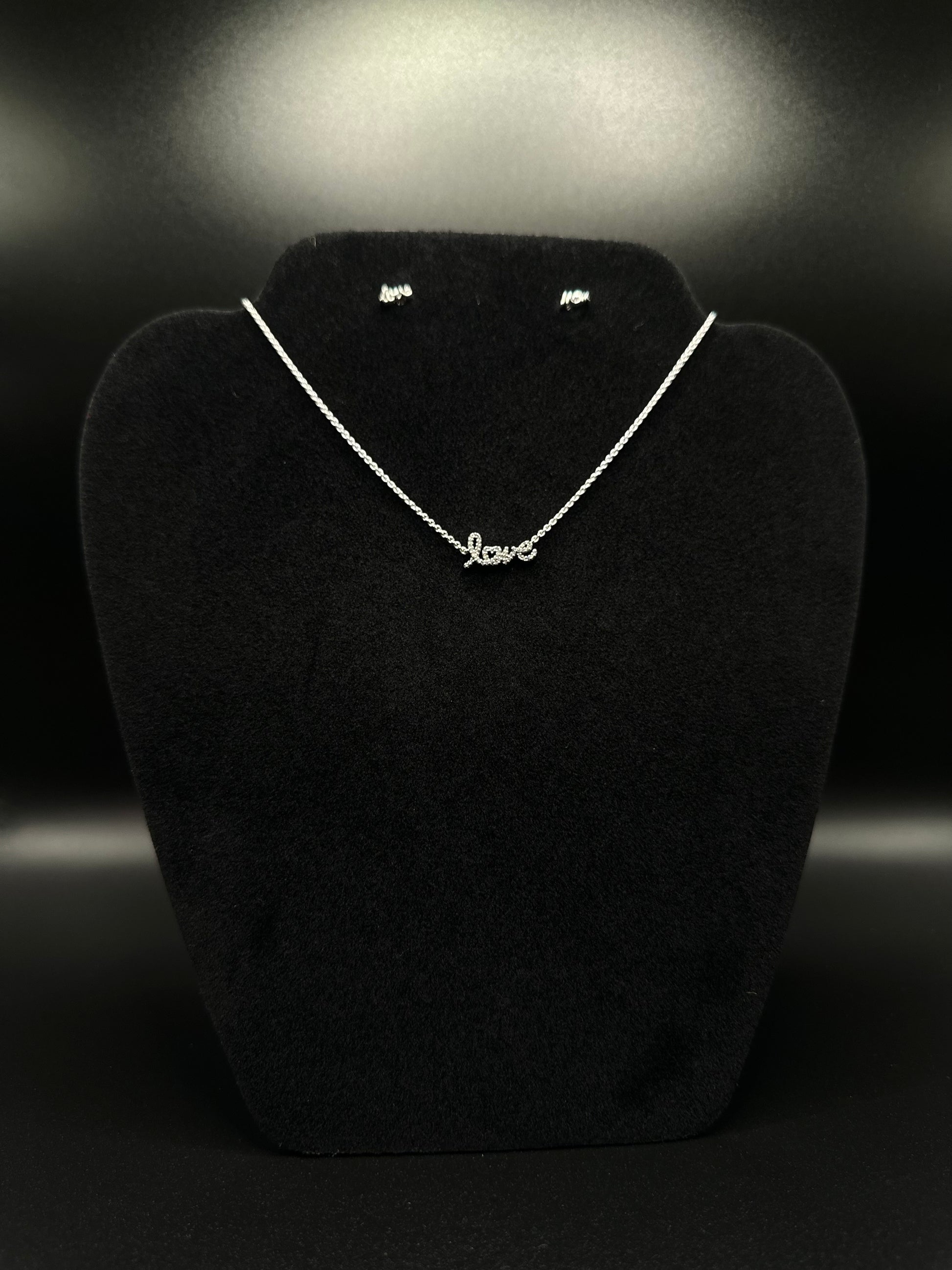 Necklace with 'love' pendant on a black stand against a dark background
